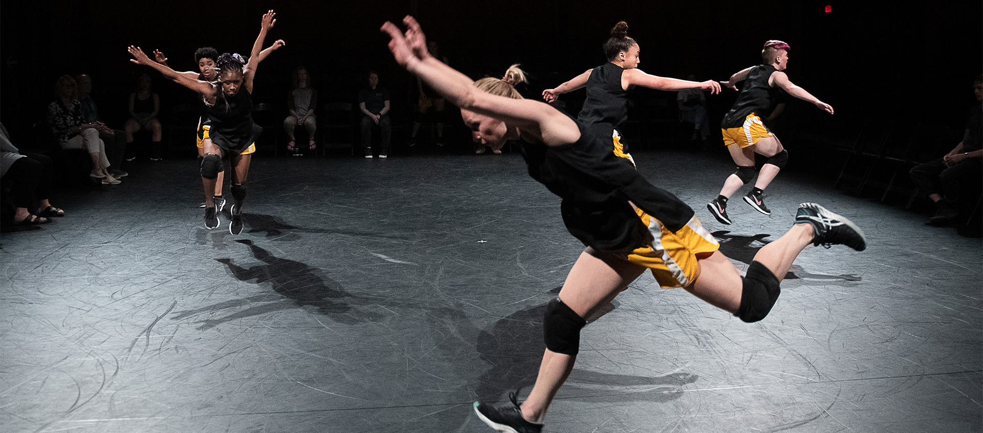 Five dancers moving across the floor