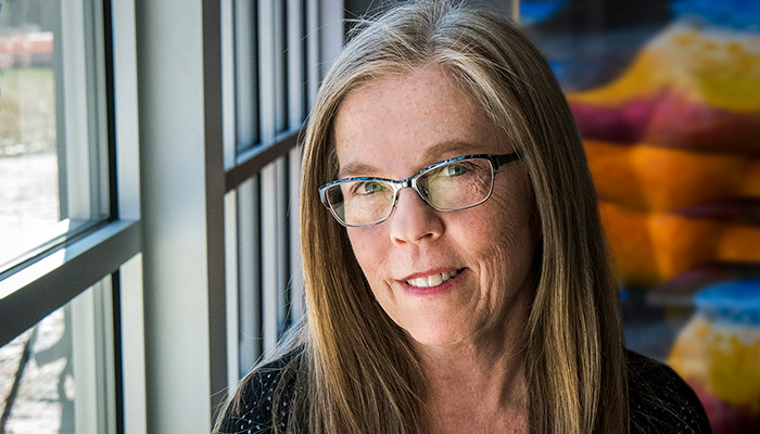 An image of Kari Gunter-Seymour from the neck up. Kari is wearing glasses and sits in front of a window.