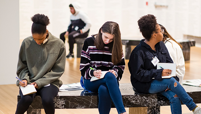 a group of young people seated in a gallery