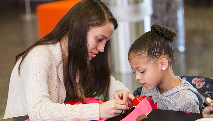 a woman helping an girl with arts and grafts