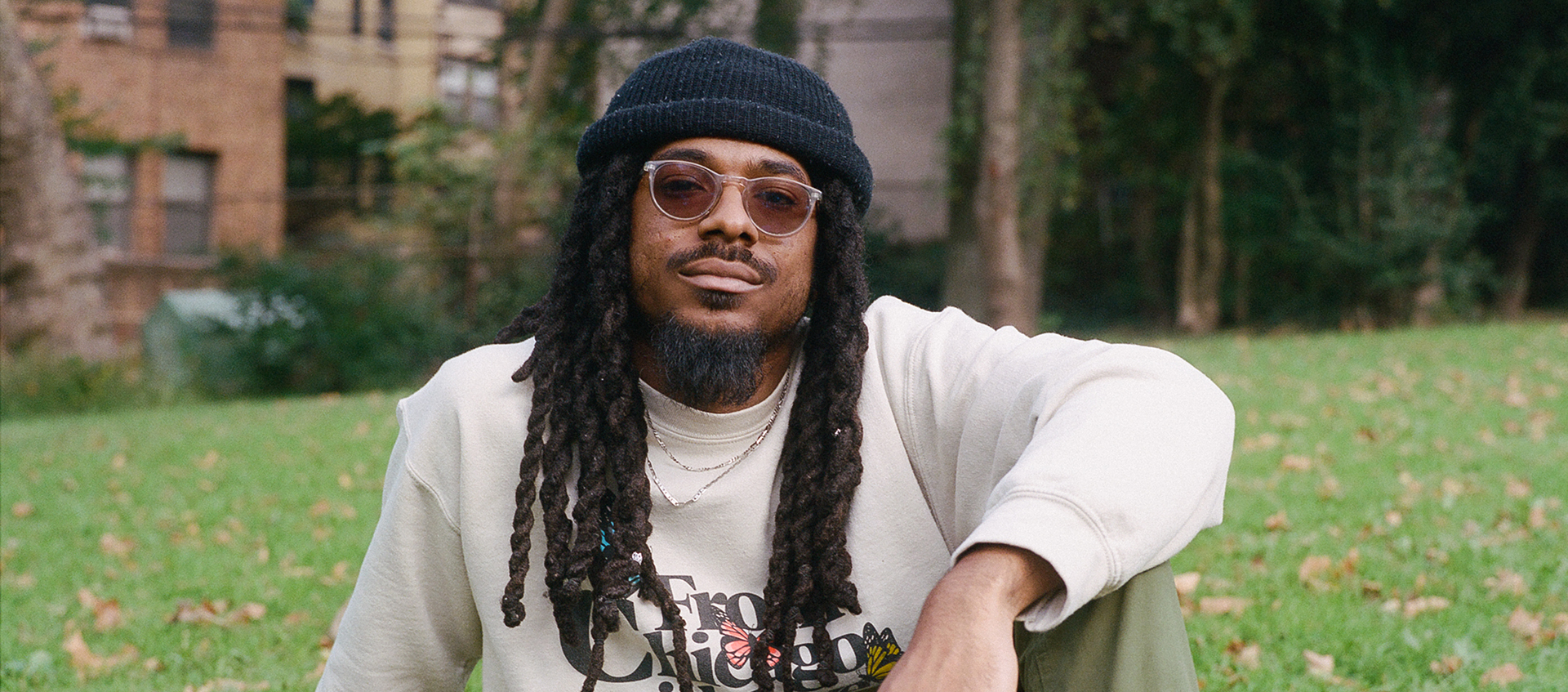 Headshot of Joel Ross. He is sitting on a lawn wearing sunglasses and a beanie.