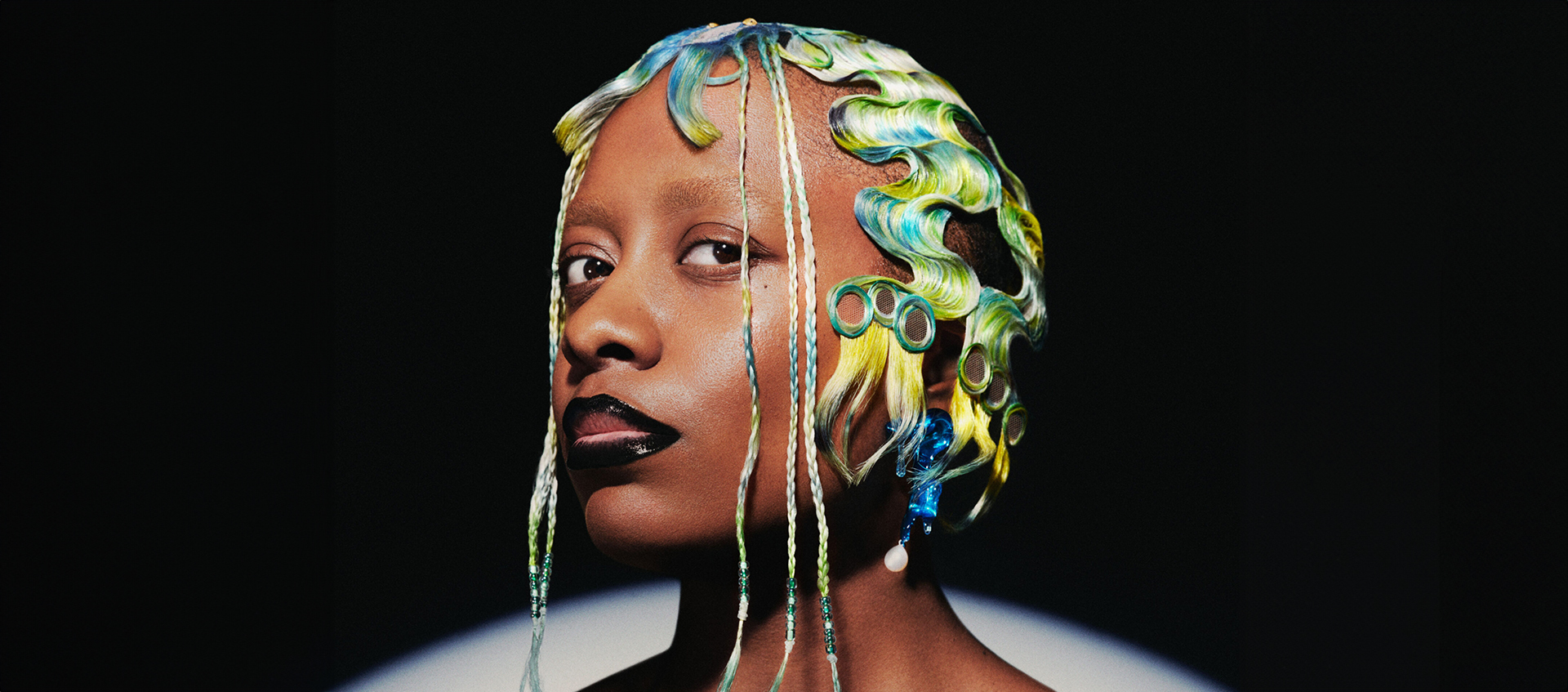 Headshot of Cecile McLorin Salvant. She has blue, yellow, and green finger waves and black lipstick.