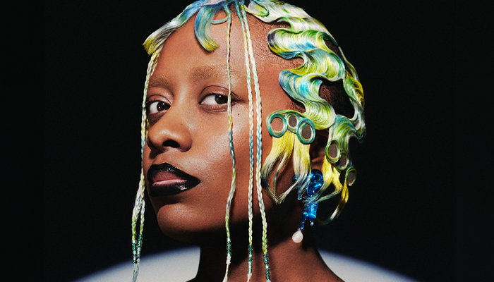 Headshot of Cecile McLorin Salvant. She has blue, yellow, and green finger waves and black lipstick.