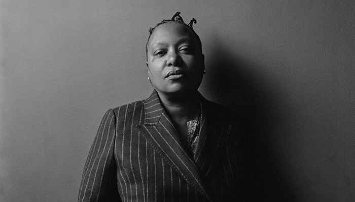 Black and white headshot of Meshell Ndegeocello wearing a pinstripe suit.