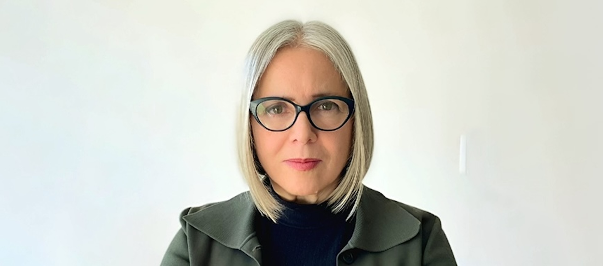 Head shot of a woman with glasses and white shoulder-length hair.