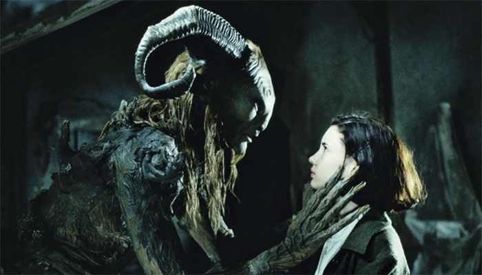 A monster with ram horns and long hair holds a hand with long fingers up to a young girl with brown hair.