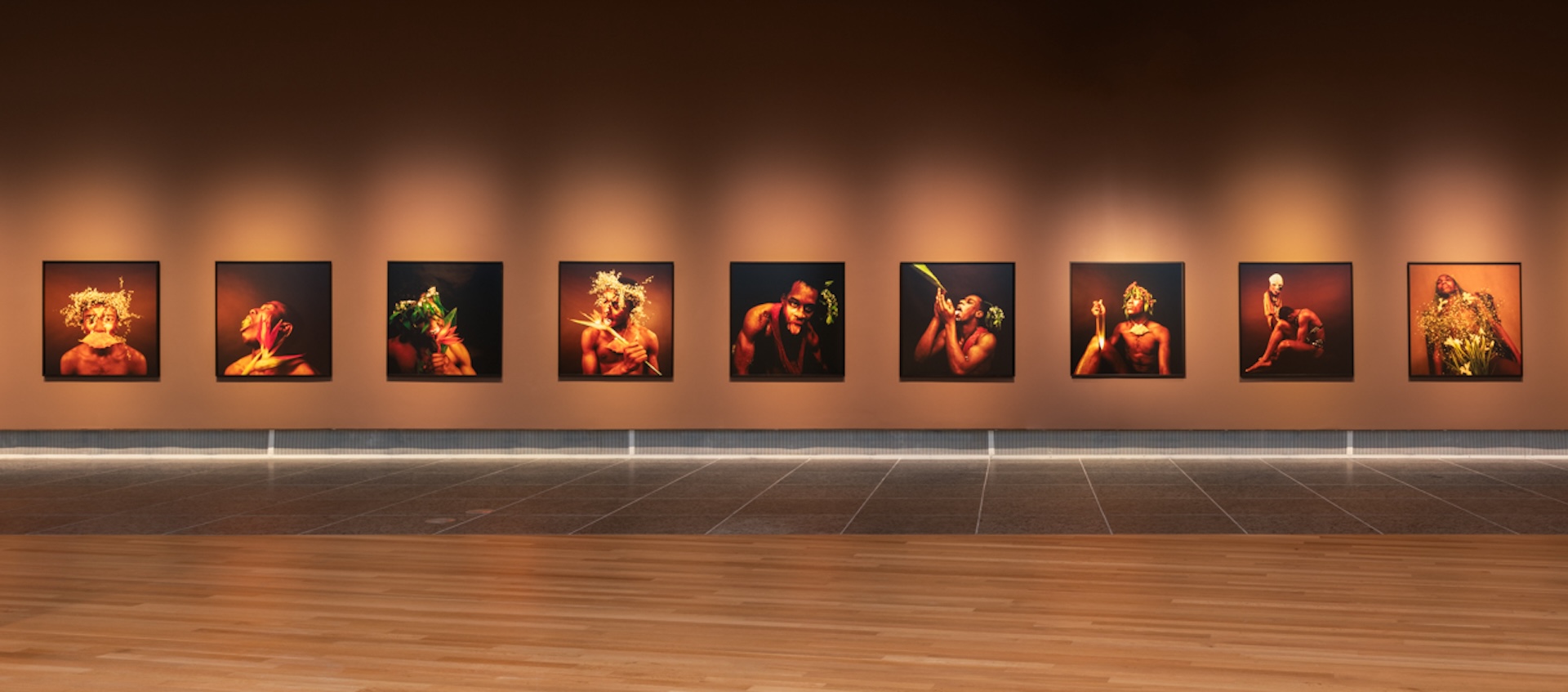 A gallery wall is hung with a row of color photographs by Rotimi Fani-Kayode.