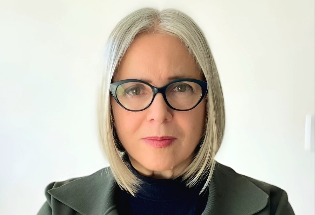 Head shot of a woman with glasses and shoulder-length white hair.